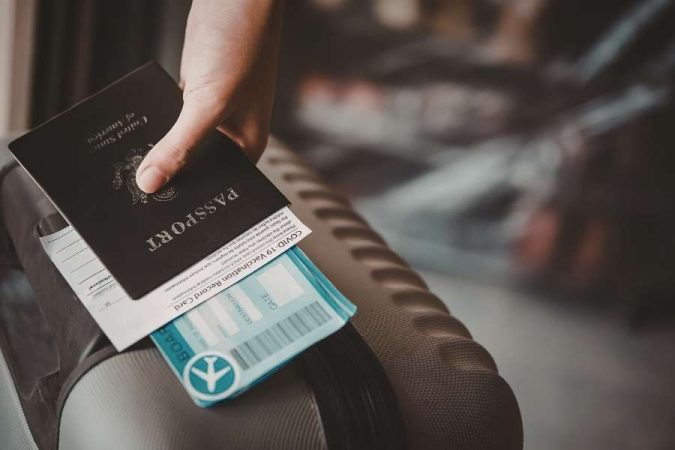 Une main tenant un passeport américain avec une carte d'embarquement, documents essentiels pour voyager avec un petit budget.