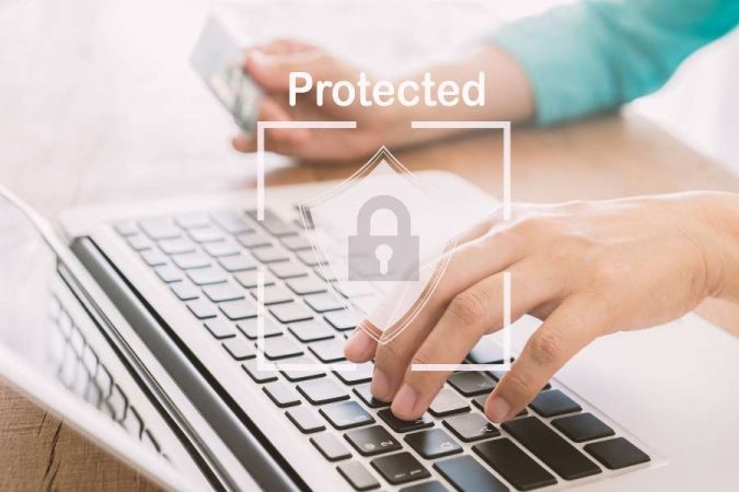 Une personne tape sur le clavier d'un ordinateur portable avec un pictogramme de cadenas de sécurité en surbrillance.